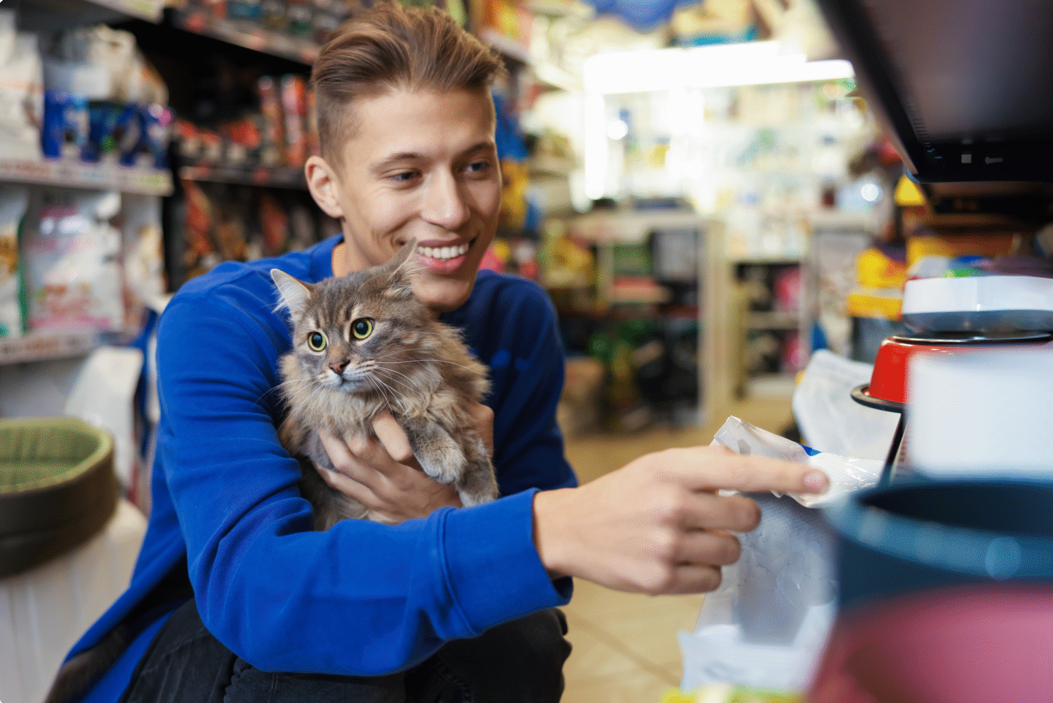 smiling man holding cat in pet store checking out