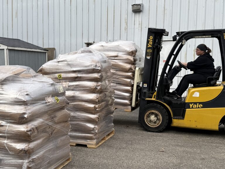 a forklift moving 3 pallets of cat food.